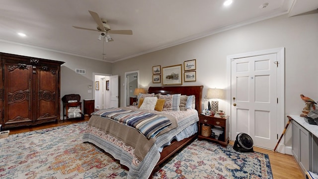 bedroom featuring ceiling fan, visible vents, ornamental molding, and light wood-style flooring