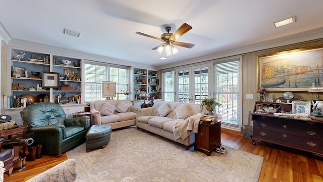 living room featuring crown molding, a ceiling fan, wood finished floors, and a wealth of natural light
