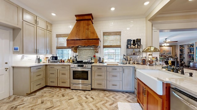 kitchen featuring crown molding, light stone counters, custom range hood, a ceiling fan, and appliances with stainless steel finishes