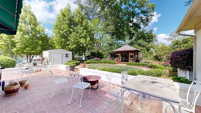 view of patio / terrace with a gazebo, an outdoor structure, a shed, an outdoor fire pit, and outdoor dining space