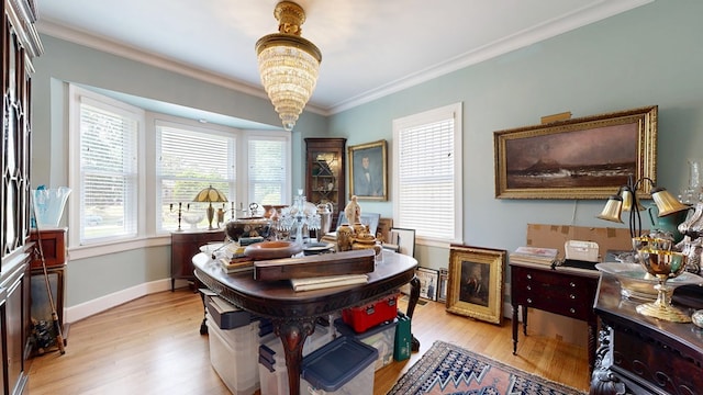 dining space with crown molding, baseboards, light wood-style flooring, and a notable chandelier
