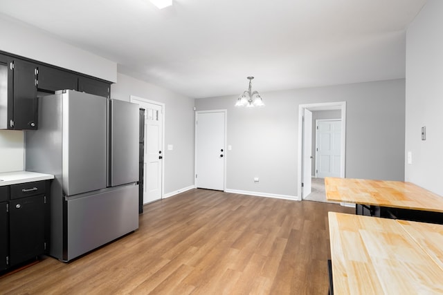 kitchen featuring stainless steel fridge, light hardwood / wood-style floors, hanging light fixtures, and a notable chandelier