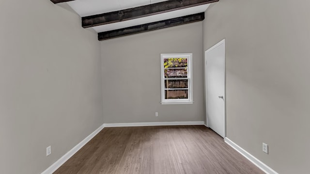 spare room featuring wood-type flooring and lofted ceiling with beams