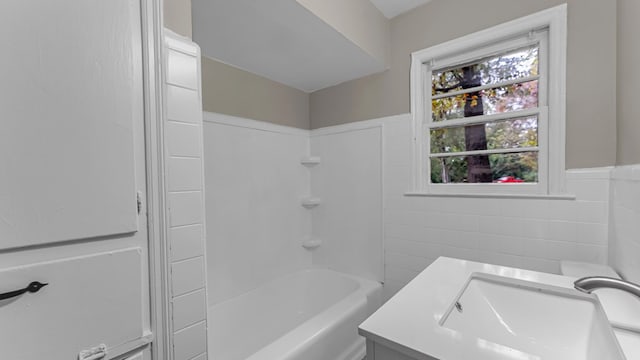 bathroom featuring vanity, shower / bathing tub combination, and tile walls