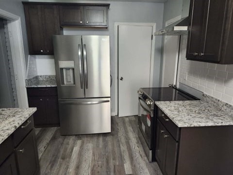 kitchen with light stone counters, dark hardwood / wood-style flooring, backsplash, dark brown cabinets, and appliances with stainless steel finishes