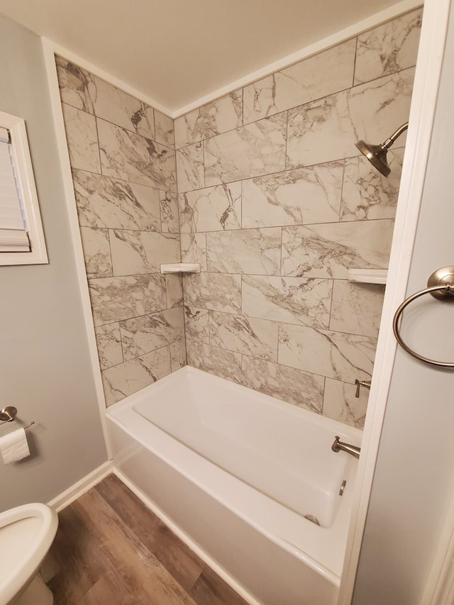 bathroom featuring hardwood / wood-style floors, toilet, and tiled shower / bath