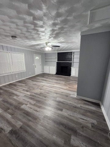 unfurnished living room featuring hardwood / wood-style flooring, ceiling fan, and a fireplace