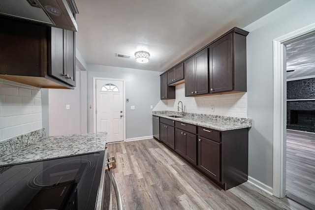 kitchen with sink, backsplash, stove, light hardwood / wood-style floors, and exhaust hood