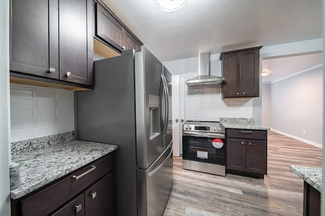 kitchen with tasteful backsplash, stainless steel appliances, wall chimney range hood, and light hardwood / wood-style floors