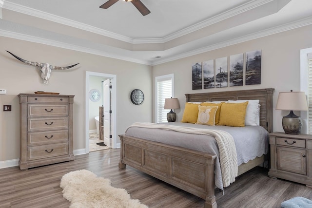 bedroom featuring connected bathroom, hardwood / wood-style flooring, ceiling fan, and crown molding