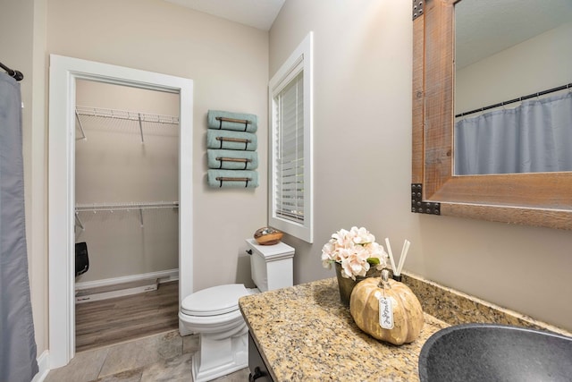 bathroom featuring walk in shower, vanity, wood-type flooring, and toilet