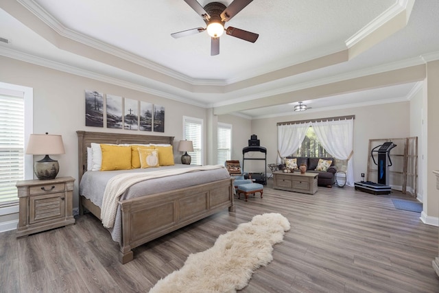 bedroom with hardwood / wood-style flooring, ceiling fan, a raised ceiling, and crown molding