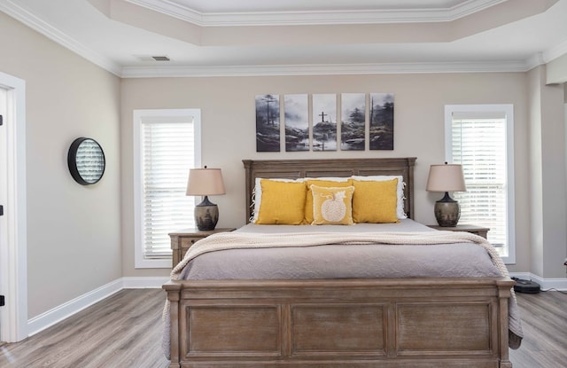 bedroom with hardwood / wood-style floors, crown molding, and multiple windows