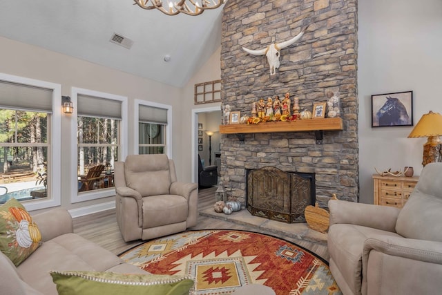 living room featuring an inviting chandelier, a fireplace, high vaulted ceiling, and light hardwood / wood-style flooring