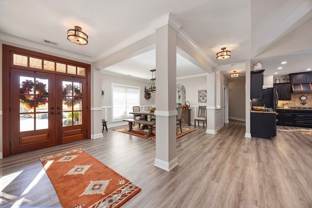 foyer with crown molding, french doors, hardwood / wood-style floors, and a textured ceiling