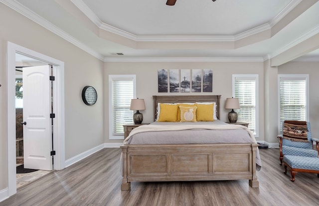 bedroom with hardwood / wood-style floors, a tray ceiling, ceiling fan, and crown molding