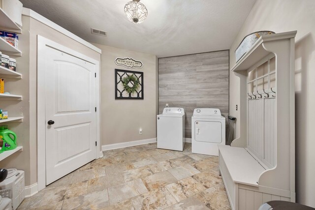 laundry area featuring a textured ceiling, separate washer and dryer, and wood walls