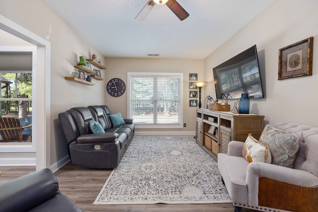 living room featuring wood-type flooring, a textured ceiling, plenty of natural light, and ceiling fan