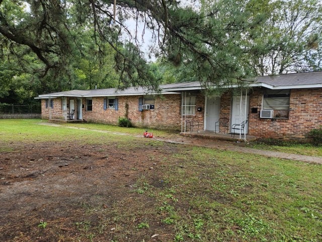 ranch-style home featuring cooling unit and a front lawn