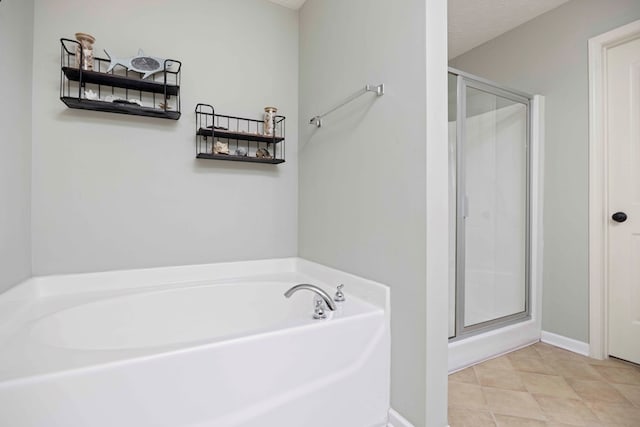 full bathroom featuring a stall shower, a textured ceiling, baseboards, and a bath