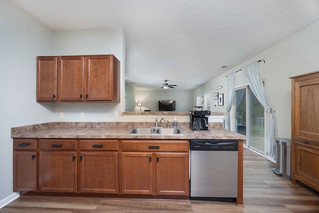 kitchen with brown cabinetry, a sink, a peninsula, and stainless steel dishwasher