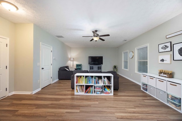 living room featuring a ceiling fan, visible vents, a textured ceiling, and wood finished floors