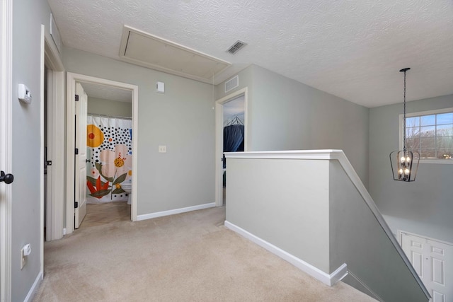 hall with light colored carpet, visible vents, attic access, an upstairs landing, and baseboards