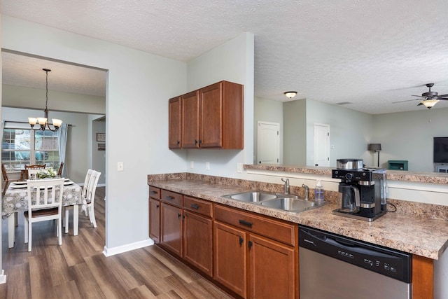 kitchen with dishwasher, dark wood-style flooring, a peninsula, a sink, and ceiling fan with notable chandelier