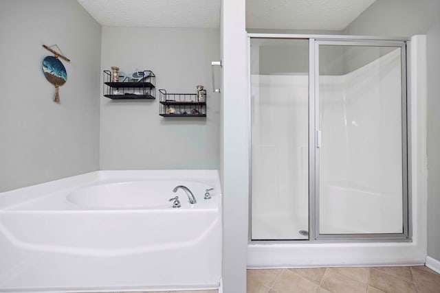 bathroom with tile patterned flooring, a garden tub, a textured ceiling, and a shower stall