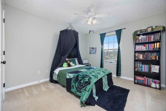 carpeted bedroom with a textured ceiling, ceiling fan, and baseboards