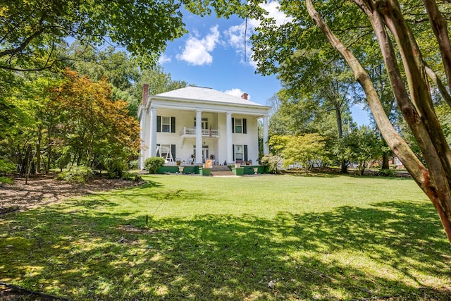 view of front facade with a balcony, a front yard, and covered porch