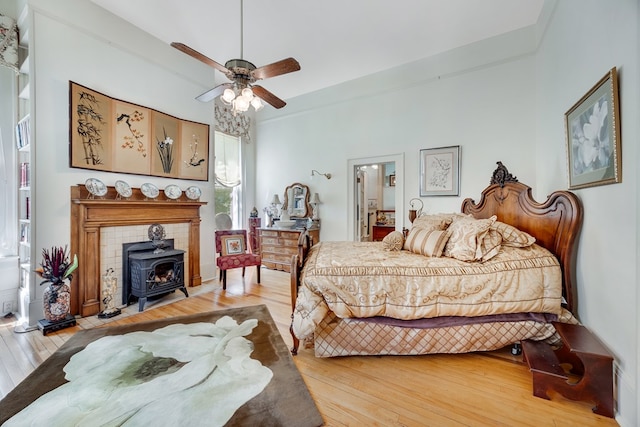 bedroom featuring hardwood / wood-style flooring, a wood stove, and ceiling fan