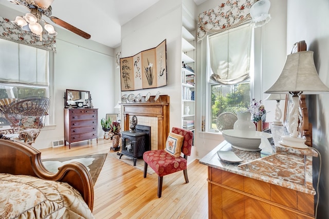 sitting room featuring a wood stove, ceiling fan, and light hardwood / wood-style flooring