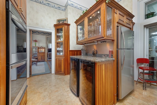 kitchen with appliances with stainless steel finishes, dark stone countertops, and beverage cooler