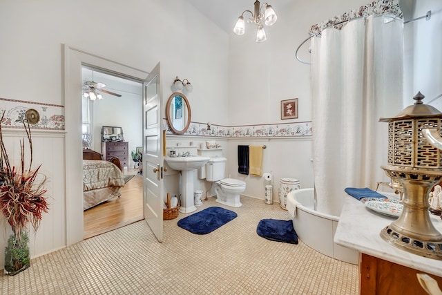 bathroom featuring tile patterned flooring, ceiling fan with notable chandelier, a bath, and toilet