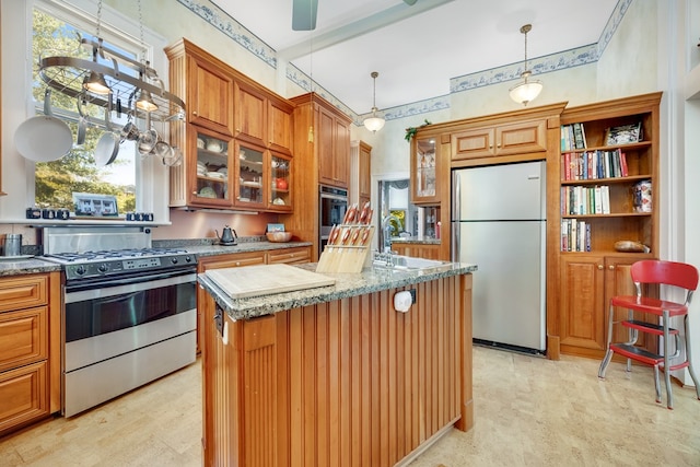 kitchen featuring sink, hanging light fixtures, a kitchen island, stainless steel appliances, and light stone countertops