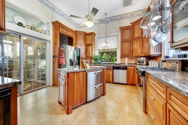 kitchen featuring sink, a center island, appliances with stainless steel finishes, pendant lighting, and dark stone counters