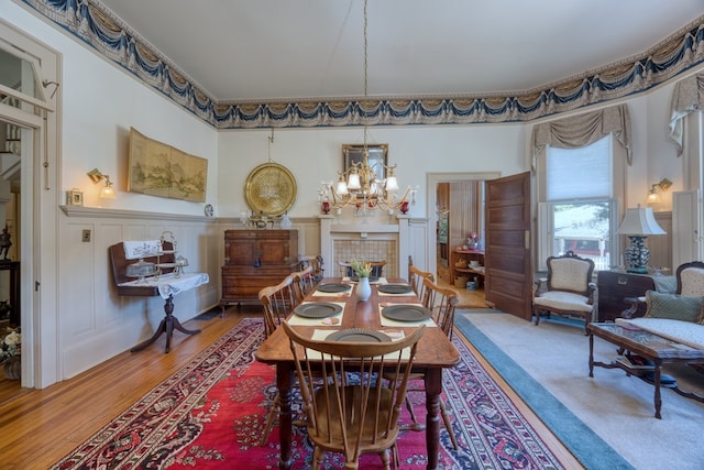 dining area featuring an inviting chandelier, hardwood / wood-style flooring, and a tile fireplace