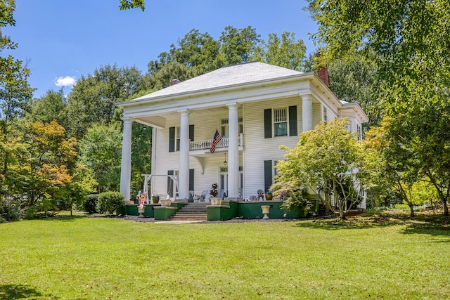 greek revival inspired property featuring a front yard and a balcony