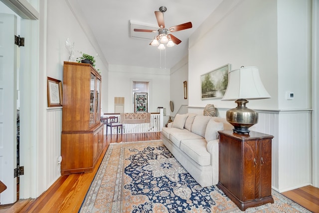 living room featuring crown molding, ceiling fan, and light wood-type flooring