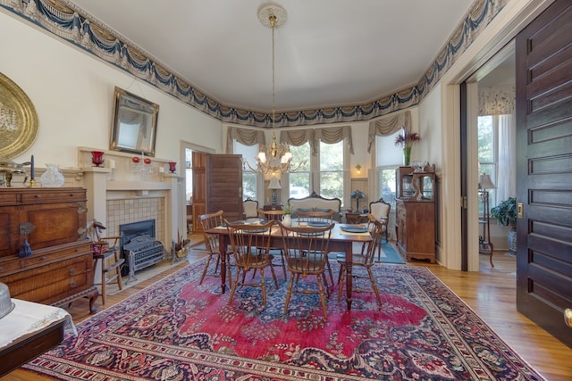 dining room featuring hardwood / wood-style floors, a fireplace, and an inviting chandelier