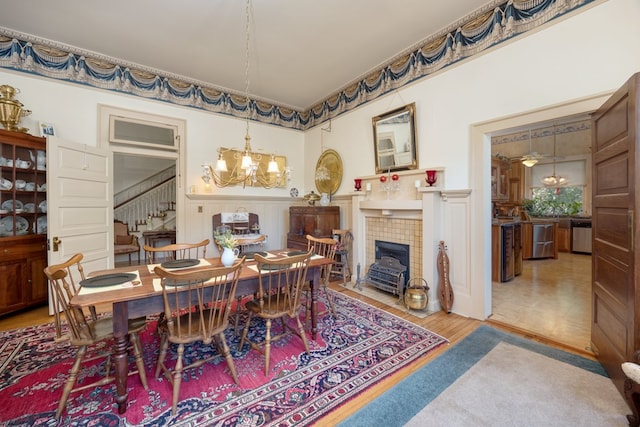 dining area featuring a tiled fireplace, a chandelier, and hardwood / wood-style floors