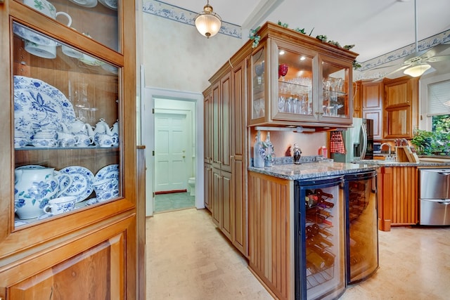 kitchen featuring light stone counters, beverage cooler, and decorative light fixtures