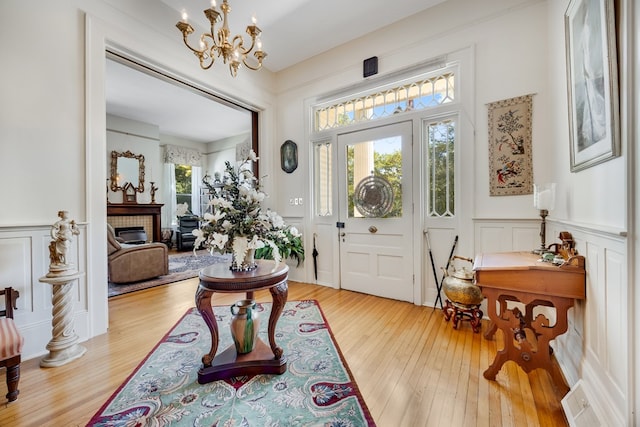 entryway with an inviting chandelier, a fireplace, and light hardwood / wood-style flooring