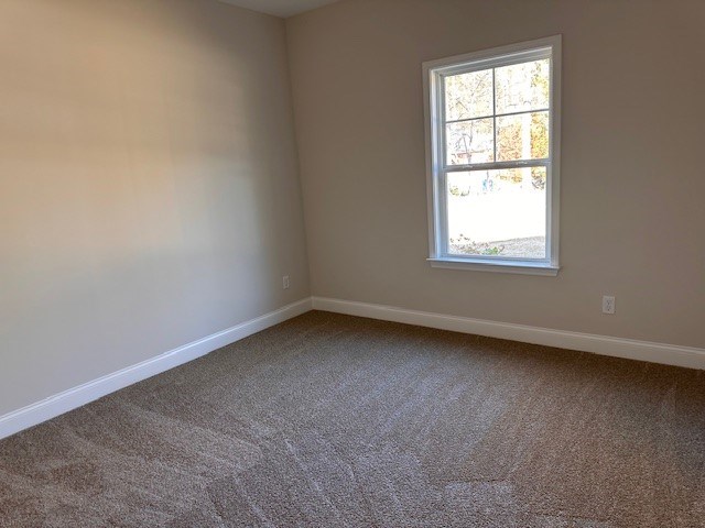 spare room featuring carpet flooring and baseboards