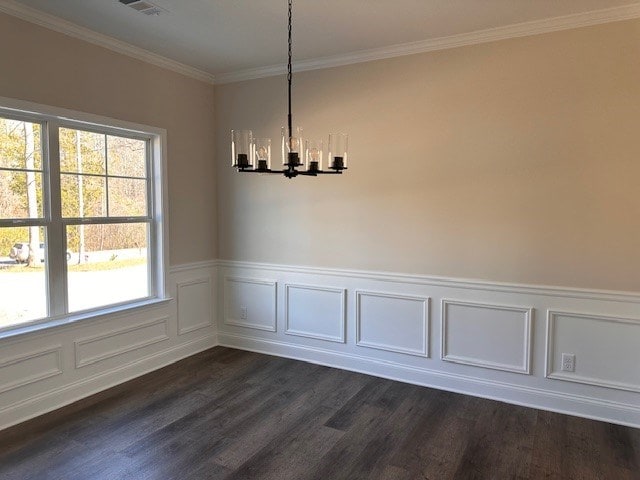 unfurnished dining area with dark wood finished floors, wainscoting, an inviting chandelier, and ornamental molding