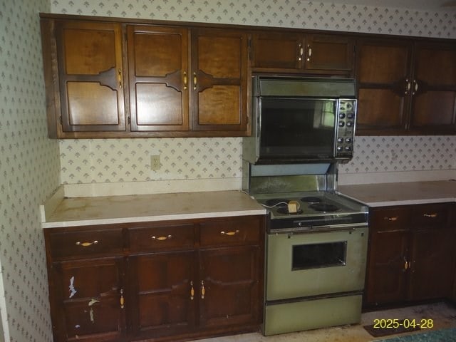1469 Wall St, Richland, GA 31825 - kitchen featuring wallpapered walls, black microwave, light countertops, electric stove, and dark brown cabinets