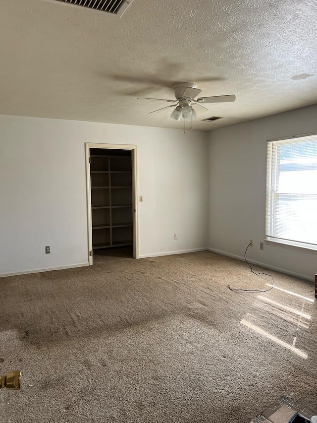 carpeted spare room with a textured ceiling and ceiling fan