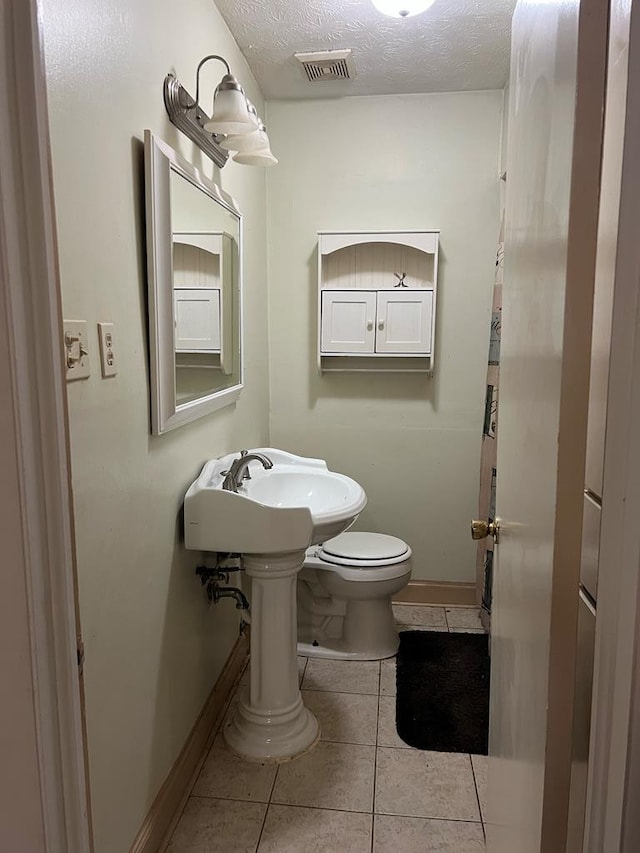 bathroom featuring tile patterned floors, a textured ceiling, and toilet