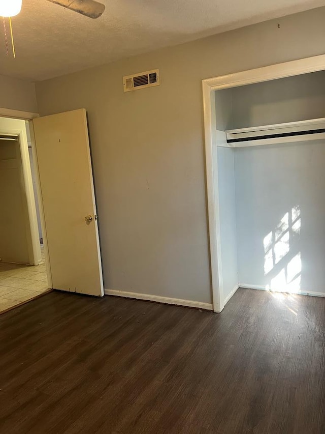 unfurnished bedroom featuring a textured ceiling, dark hardwood / wood-style flooring, and a closet